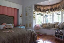 Modern window seat with storage drawers in window bay in dramatic, antique-style girl's bedroom in historical house