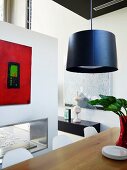 Pendant lamp above dining table and modern painting on partition wall