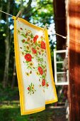 Floral tea towel hanging on washing line outside wooden cabin in woodland