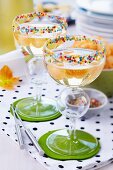 Champagne with melon balls in cocktail glasses decorated with sugar sprinkles on rims