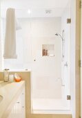 Modernes Bad, abgetrennter Duschbereich mit Glastür, sandfarbene Fliesen an Wand