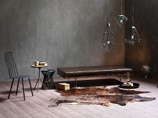 Brown leather bench, animal-skin rug and Industrial-style, metal pendant lamps in corner of room