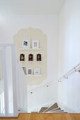 View down staircase with small gallery of framed pictures on beige panel in classic ogee shape
