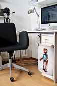 Dark grey swivel chair at desk with computer; clips holding colourful illustration of robot on filing cabinet