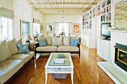 Offener Wohnraum im Countrystil mit Sofa, Couchtisch, Einbauregalen, Kamin, Dielenboden & Holzbalkendecke