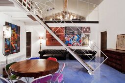 Filigrane Galerie Stahltreppe auf hellblauem Kunstharzboden in luftigem Wohnraum vor künstlerischer Bildergalerie