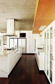 Modern, white kitchen with free-standing central island on dark wood floor