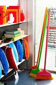 Brightly coloured, designer brooms and various home accessories on shop shelving