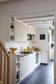Open-plan kitchen with white cupboard doors and grey tiled floor