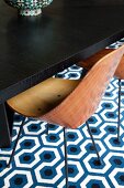 Retro Stuhl mit Holzschale vor dunklem Eichentisch, Retro Teppich mit geometrischem Muster