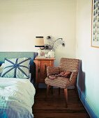 Sessel im Fiftiesstil neben Nachtkästchen und teilweise sichtbares Bett in Schlafzimmerecke