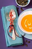 Sprig of sea buckthorn decorating place setting with bowl of pumpkin and sea buckthorn soup