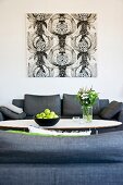 Fruit bowl on classic coffee table between grey sofas and black and white graphic artwork on wall