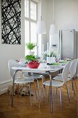 Dining room with white shell chairs and matching dining table with retro-style metal frame in traditional interior with modern ambiance