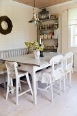 Dining table, white kitchen chairs, bench and storage containers on shelf unit in background