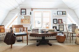 Books on antique wooden table in white, wood-clad room with rustic ambiance
