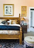 Elegantes Doppelbett mit geschnitztem Holzgestell, davor Sitzhocker in orientalischem Stil im Schlafzimmer
