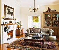 Antique coffee table and sofa on Oriental rug in traditional living room with open fireplace