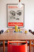 Gerahmtes Vintage Plakat als Dekoration am schlicht gedeckten Kaffeetisch mit gelbem Geschirr im Retrolook
