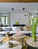 Round wooden tables with metal frames in front of purist designer sofa