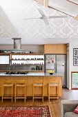 Modern kitchen area with wooden counter and bar stools in open-plan interior