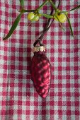 Christmas tree bauble and mistletoe on red gingham cloth