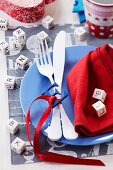 Blue plate, cutlery, napkin and alphabet decorations on place mat