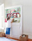 Child in front of shelves decorated with vintage books and letters spelling FRED in child's bedroom