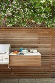 Shelf next to barbecue mounted on modern wooden fence of terrace