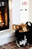 Logs in animal-skin bag next to fire in masonry fireplace