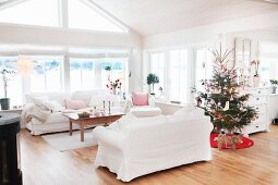 weiße Sofagarnitur und geschmückter Weihnachtsbaum in offenem Wohnbereich mit ländlichem Flair