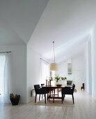 Essplatz mit gepolsterten Stühlen auf Dielenboden in offenem Wohnraum mit minimalistischem Flair