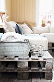 Couch made from stacked wooden pallets and pale cushions in rustic interior