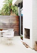 Open fireplace in white, outdoor chimney breast of Australian beach house with terrace and screen fence of narrow wooden slats