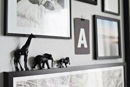 Gallery of pictures with tiny, black animal figurines on picture frame