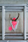 Hunting trophy painted neon pink with star pendant hanging on concrete wall
