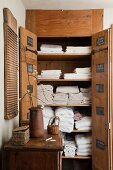 Open, rustic, wooden linen closet built into niche