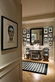 Framed portrait of woman on wall of hallway with view of Fornasetti chairs and black and white houndstooth rug