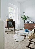 Eclectic, youthful interior with Chippendale-style TV cabinet on castors, sheepskin rugs and ride-on toy car on chest of drawers