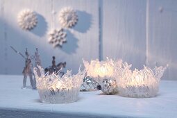 Weihnachtliche Windlichter geformt aus transparenten Heisskleberfäden