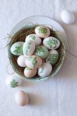 Easter eggs decorated with botanical patterns (decoupage) in nest of straw in bowl