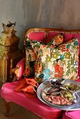 Canapés on silver platter in front of ethnic scatter cushions on deep pink couch