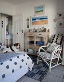 Dog on bed, white bamboo chair with cushions and cabinet with glass doors in rustic-maritime bedroom