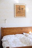 Bett mit Holz Kopfteil und weiße Bettwäsche an tapezierter Wand