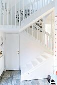 Treppe mit Holzgeländer aus weiss lackierten Stäben in offenem Treppenhaus
