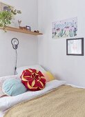 Flower-shaped cushion on bed below wall lamp and shelf in corner