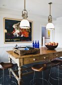 Rustic table and stools under vintage, industrial pendant lamps