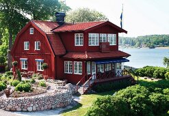 Old, Swedish wooden house with Falu-red facade in park-like gardens by the sea