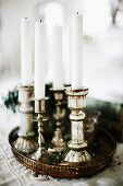 White candles in silver candlesticks on vintage tray