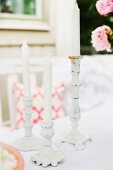 White candles in white, vintage candlesticks in romantic, outdoor setting
